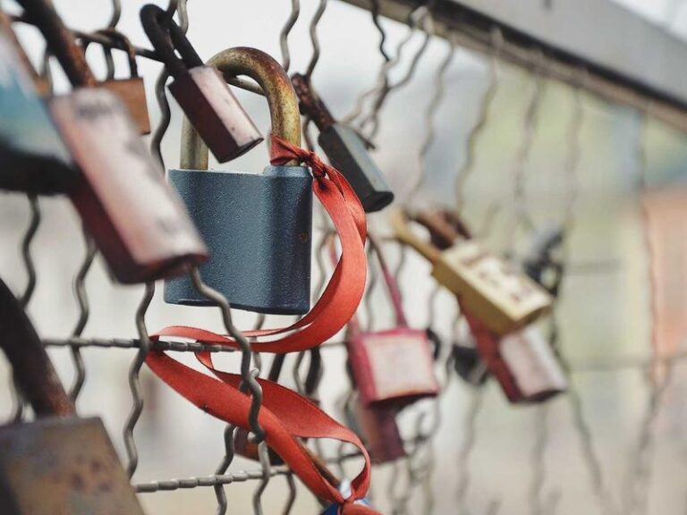 Cadenas avec ruban rouge attaché à une grille.